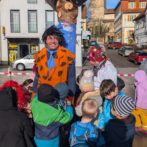 Wolfgang Gogel – als Fred Feuerstein verkleidet – wird von Kindern an einem Narrenbaum festgebunden